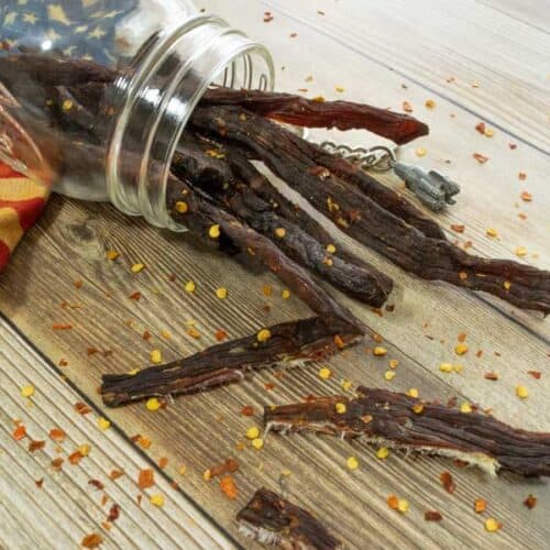 Jerky in jar with red pepper flakes on wood