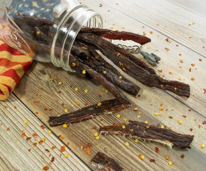 Jerky in jar with red pepper flakes on wood