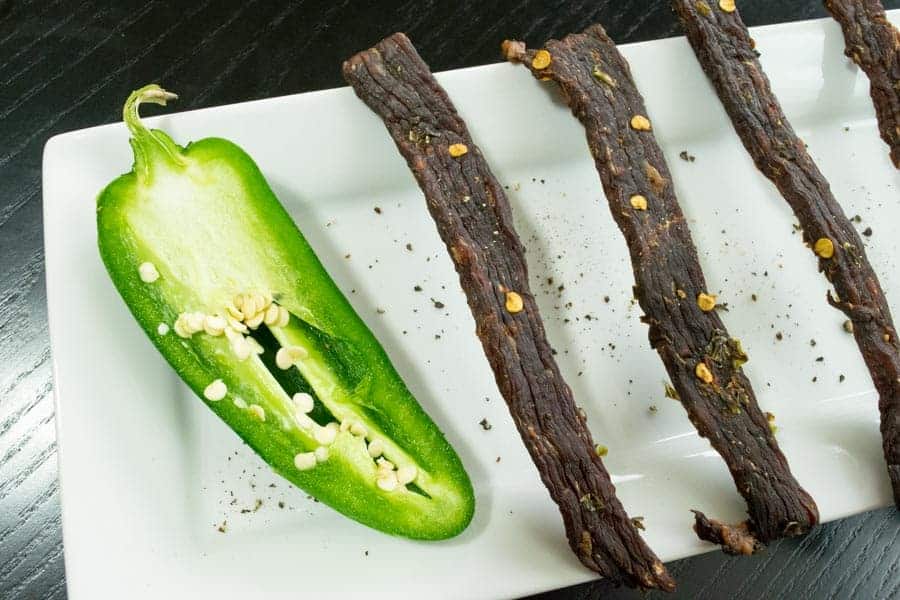 South Texas Jalapeno jerky on white dish with jalapeno cut in half