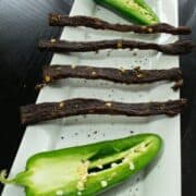 South Texas jalapeno jerky on white dish with fresh jalapenos cut in half