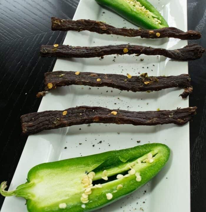 South Texas jalapeno jerky on white dish with fresh jalapenos cut in half