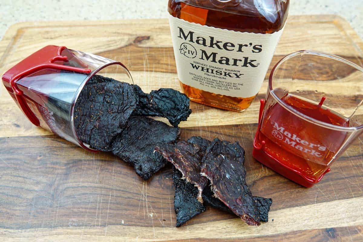 beef jerky on cutting board with bourbon bottle