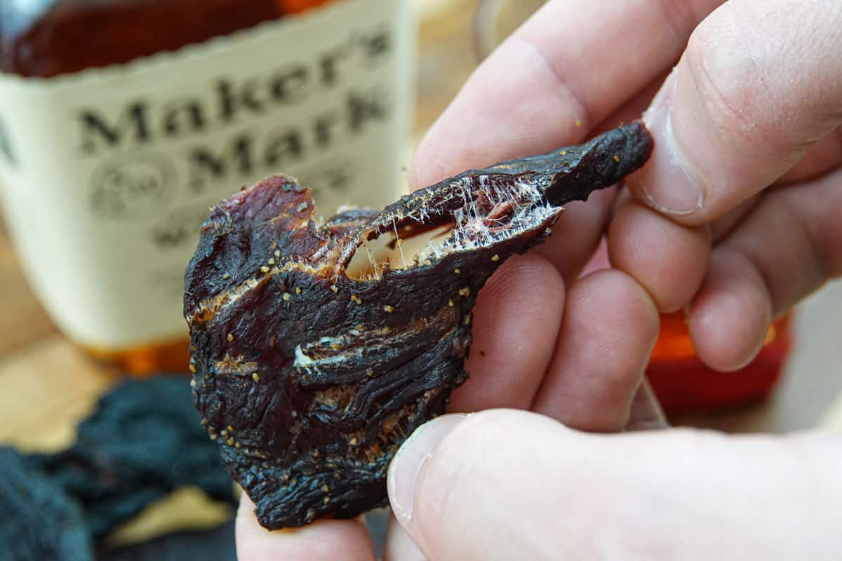 Bending a piece of beef jerky in half to see if it's finished drying