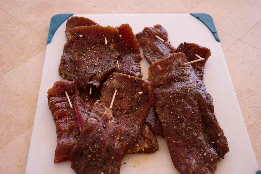 Garlic Black Pepper Beef Jerky with toothpicks laying on cutting board