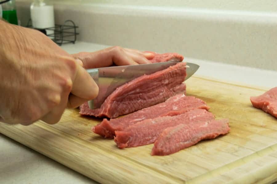 Slicing meat for jerky on cutting board