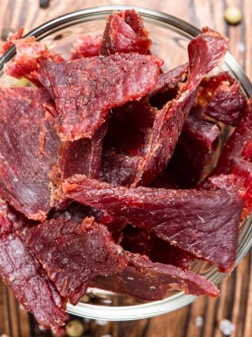 Beef jerky in a glass bowl on wood background