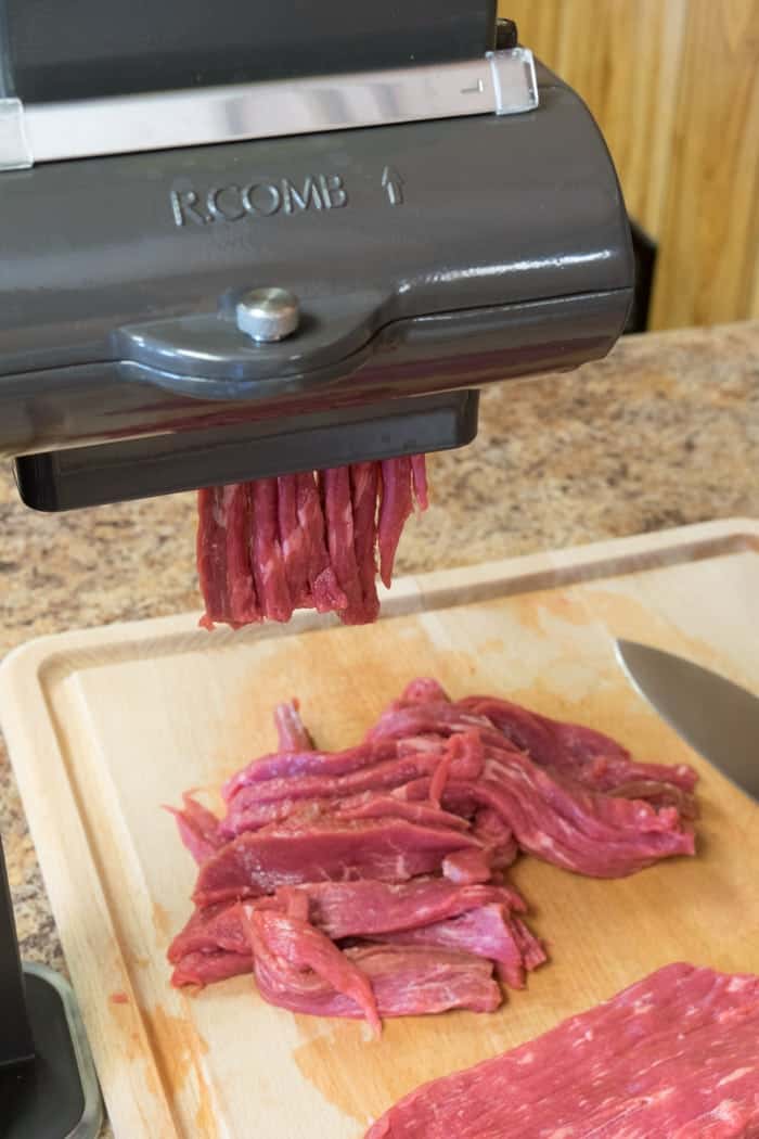 Jerky meat slicer slicing beef onto cutting board
