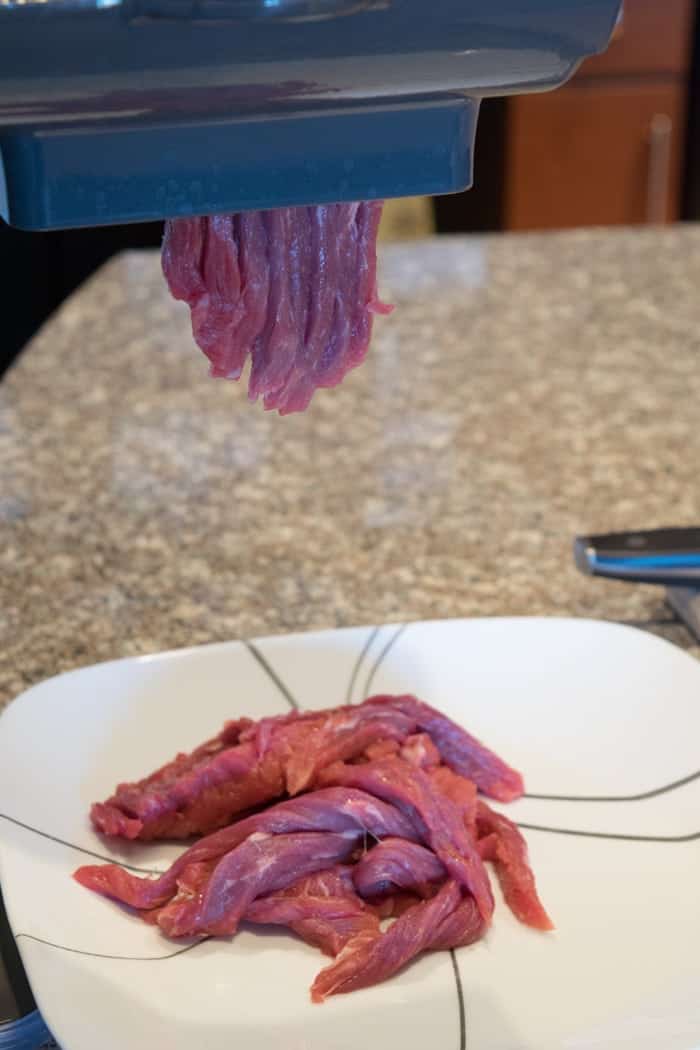 Beef Top Round being sliced in jerky slicer