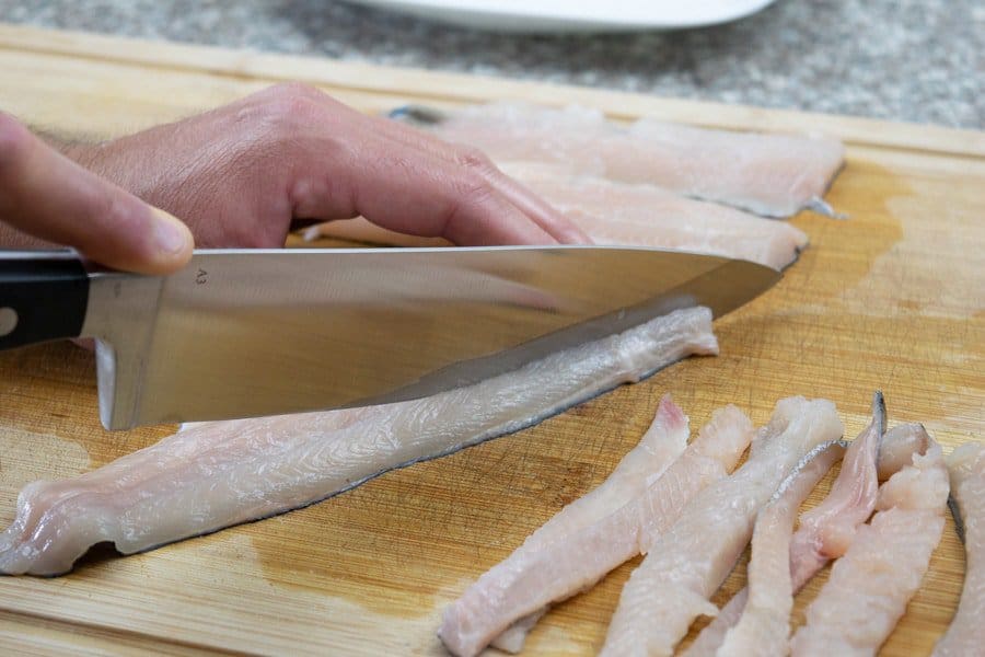 Slicing trout into strips for jerky on cutting board with knife