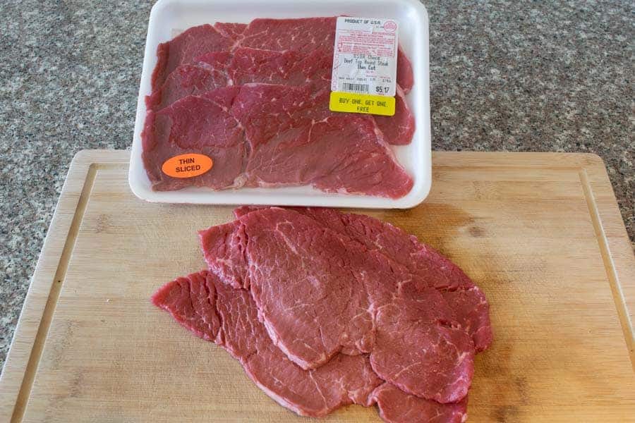 Thinly sliced beef top round on cutting board for jerky