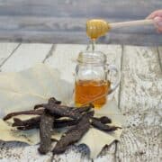 Peppered Honey Deer Jerky finished on wood boards with jar of honey