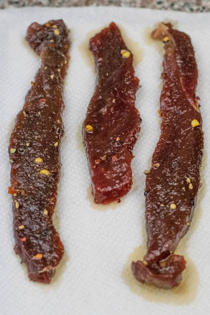 Peppered Honey Deer Jerky being patted dry on paper towels