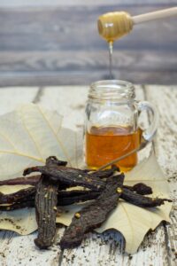 Peppered honey deer jerky on a leaf with a jar of honey with wood background