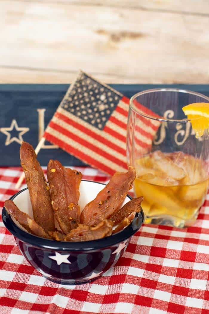 Citrus Bourbon Jerky with flag and bourbon in a glass