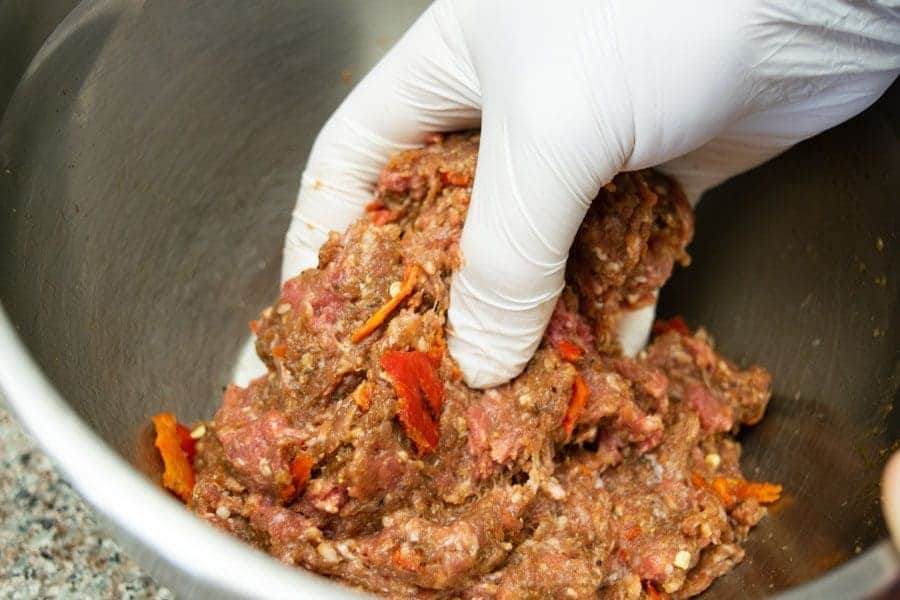 ground beef mixed by hand in bowl for jerky