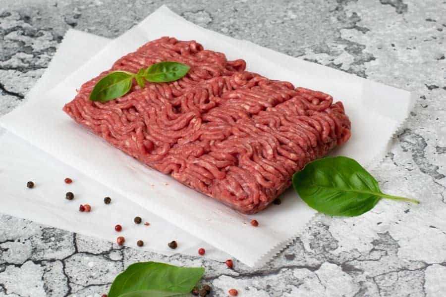 Ground Beef with basil on parchment paper and marble