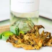 maitake mushroom jerky on plate with white wine bottle and cork