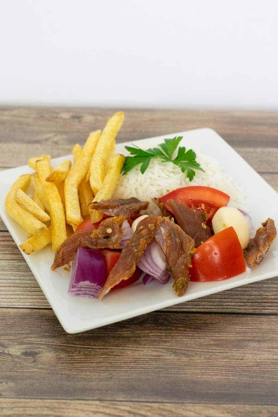 Peruvian Turkey jerky on a plate with rice and french fries