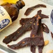 Deer jerky on platter with glass of beer and a coors original beer bottle