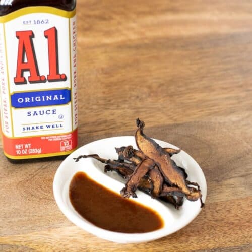 A1 sauce bottle and mushroom jerky on white plate on table
