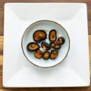 Shiitake jerky in bowl on white plate on wooden table