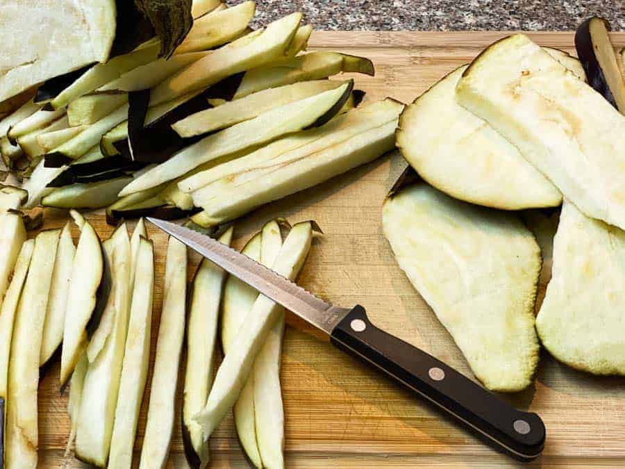 knife on cutting board with sliced eggplant