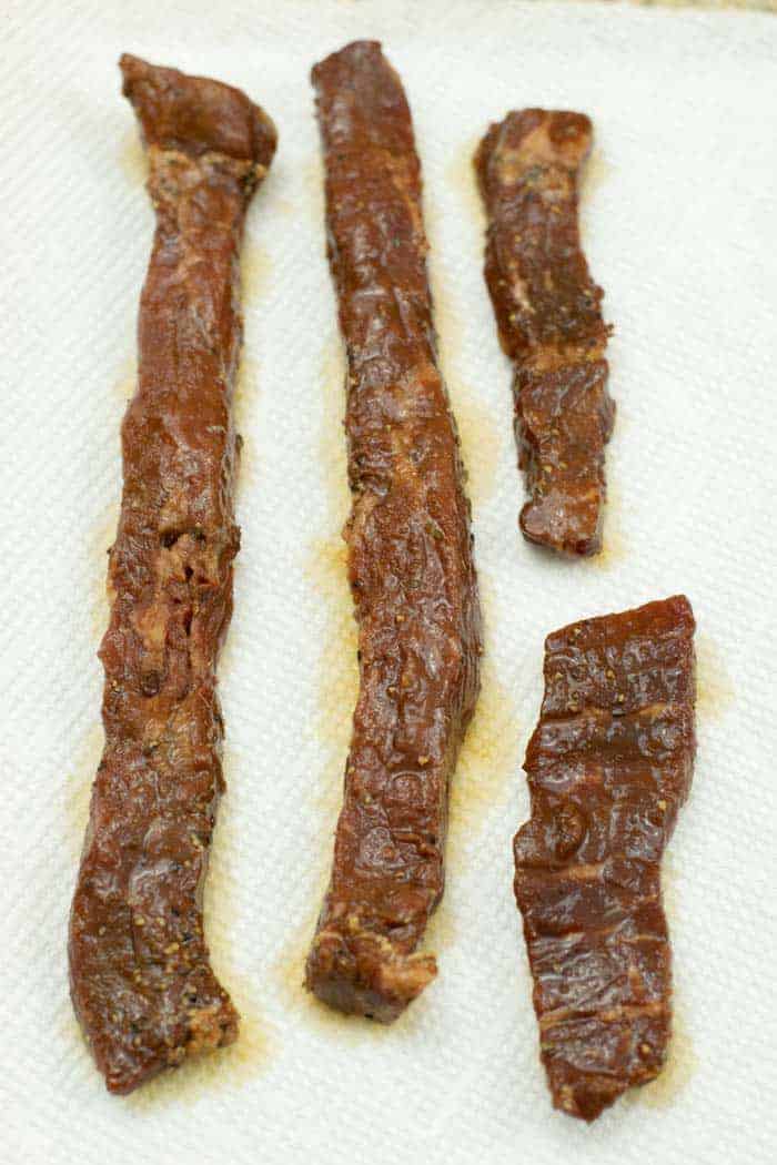 Patting jerky strips of marinade dry with paper towels