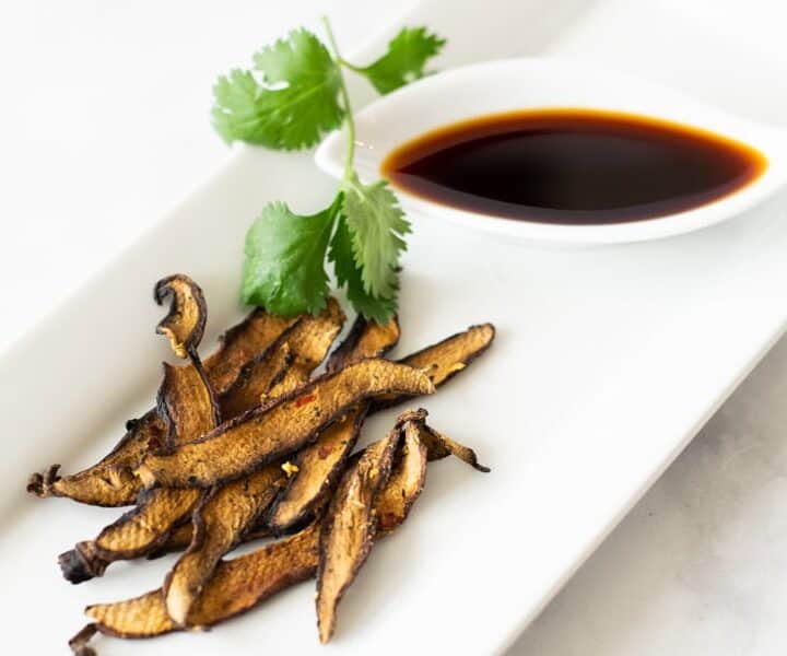 Mushroom Jerky on white plate with soy sauce on side