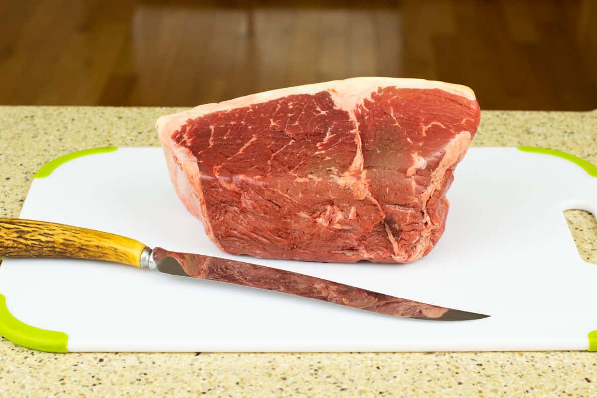 beef roast on cutting board with knife