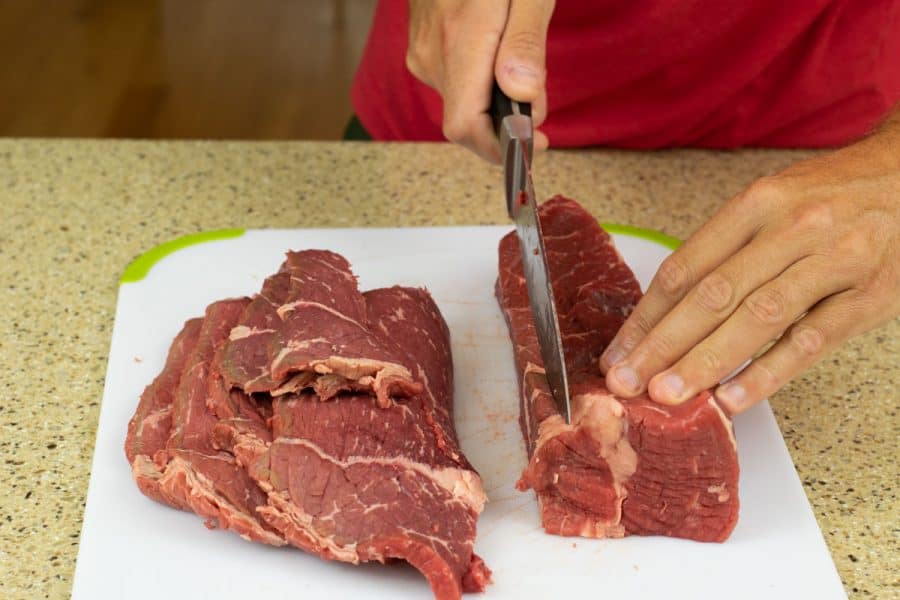 Slicing beef into strips for jerky on cutting board