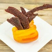 Tangy flavored beef jerky in orange bell pepper on plate