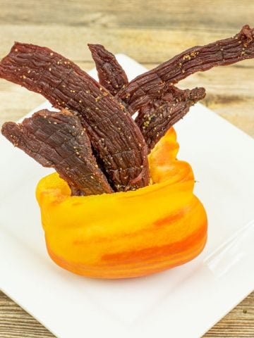 Tangy flavored beef jerky in orange bell pepper on plate