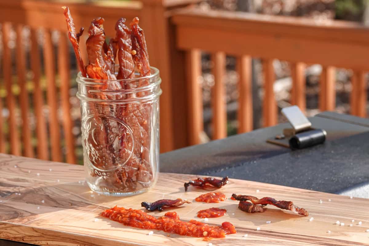 Chicken Jerky in glass on cutting board with spices