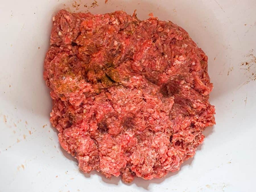 Ground meat mixed with seasoning in bowl