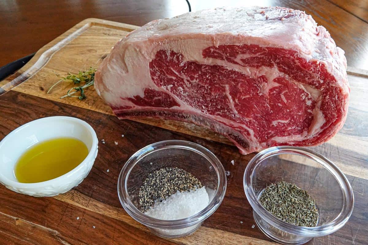 Prime rib roast on cutting board with spices in dishes