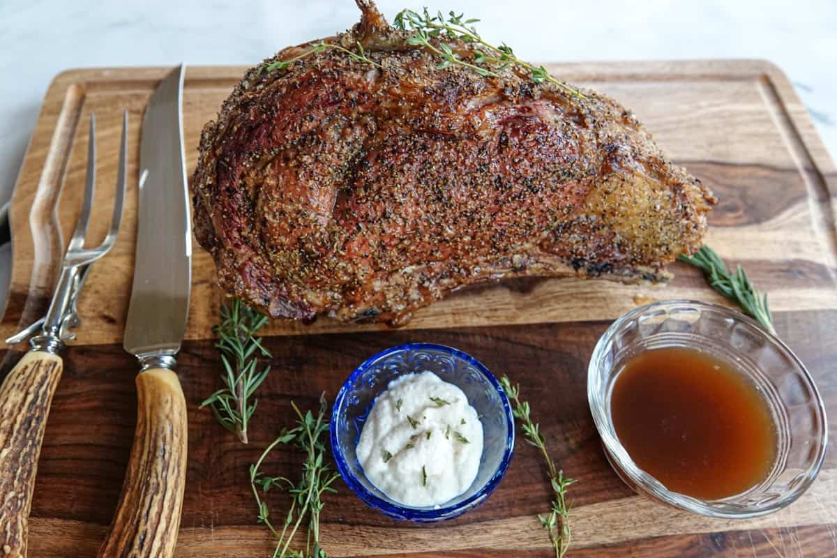Prime rib on cutting board with horseradish, au jus, and knife & fork