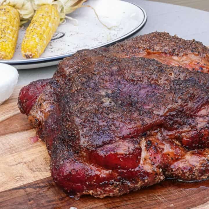 smoked pork butt on cutting board with corn in background