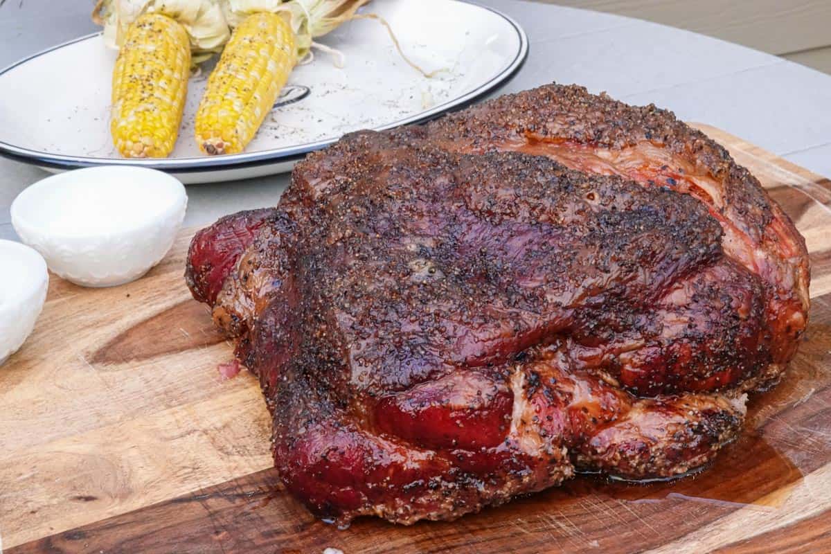 smoked pork butt on cutting board with corn in background
