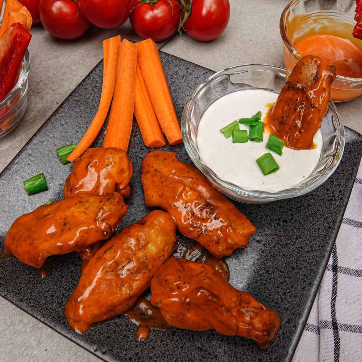 Smoked Chicken wings on plate with ranch sauce, carrots, and tomatoes
