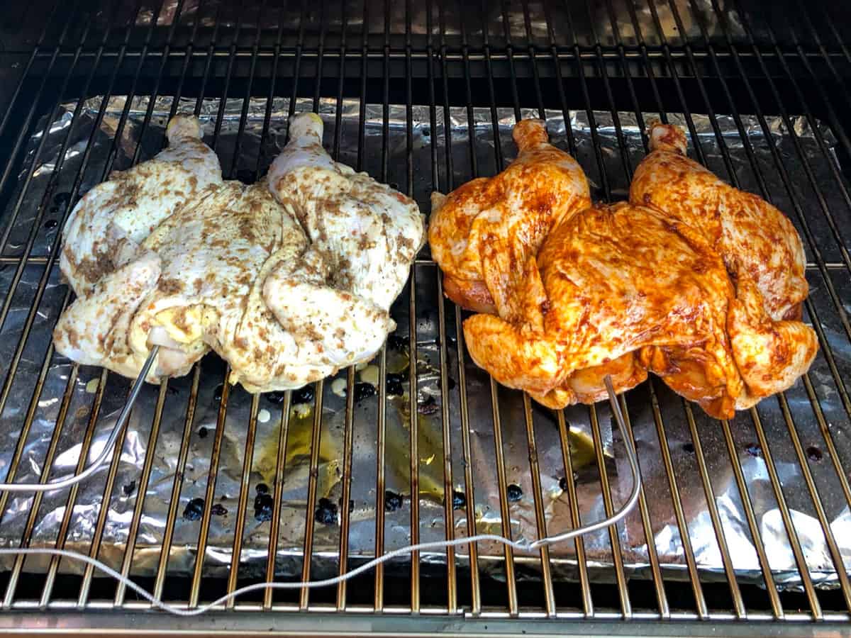 Two chickens on grill with meat probes inserted into breast