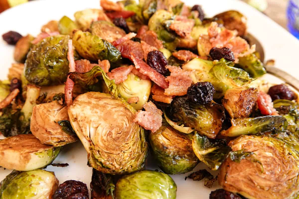 Close up view of smoked brussel sprouts topped with bacon and cranberries
