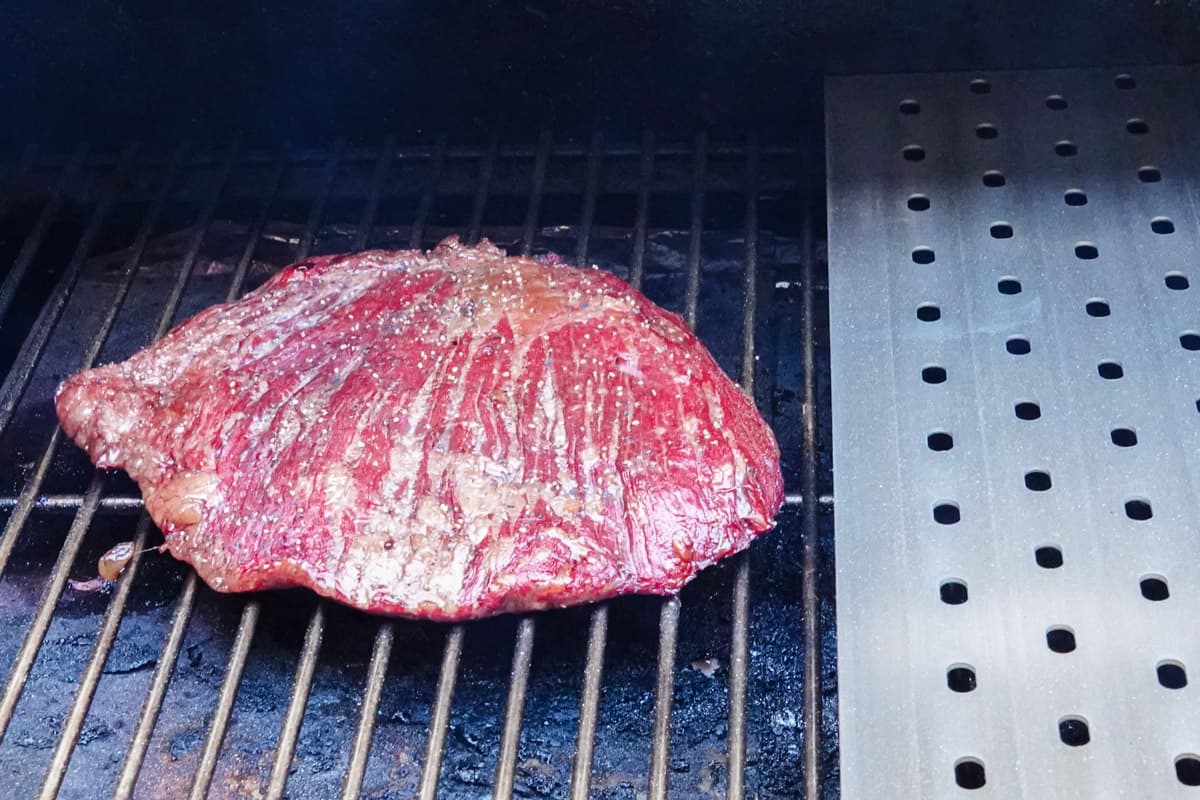 Flank steak smoking on smokers grill grate