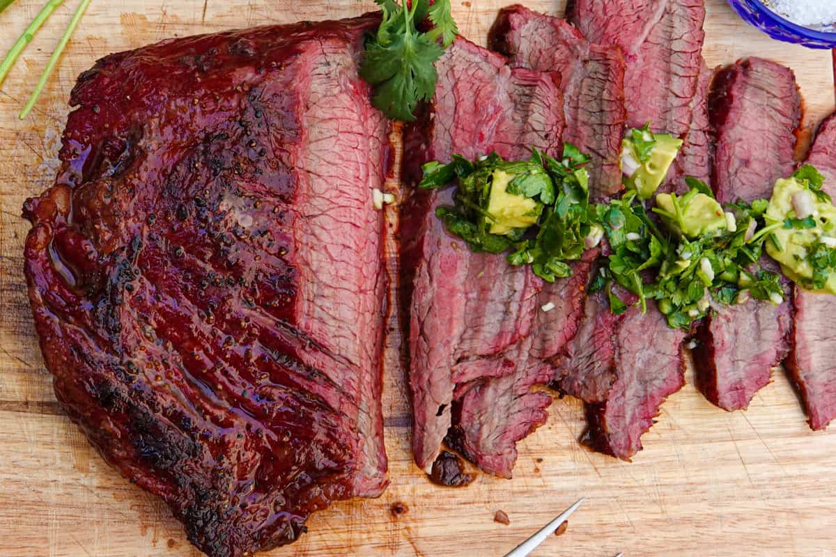 Flank steak sliced on cutting board with chimichurri sauce