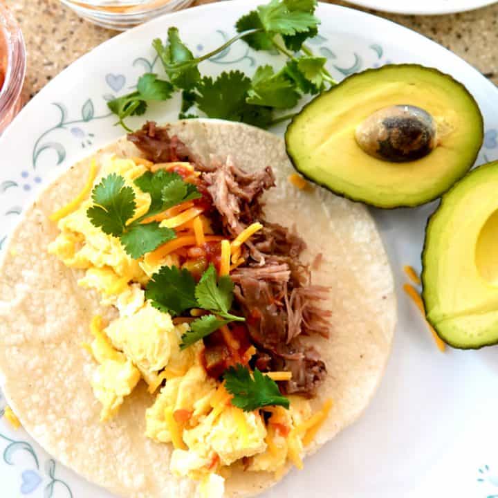 scrambled eggs, pulled pork taco topped with salsa, cheddar cheese and cilantro. Halved avocado