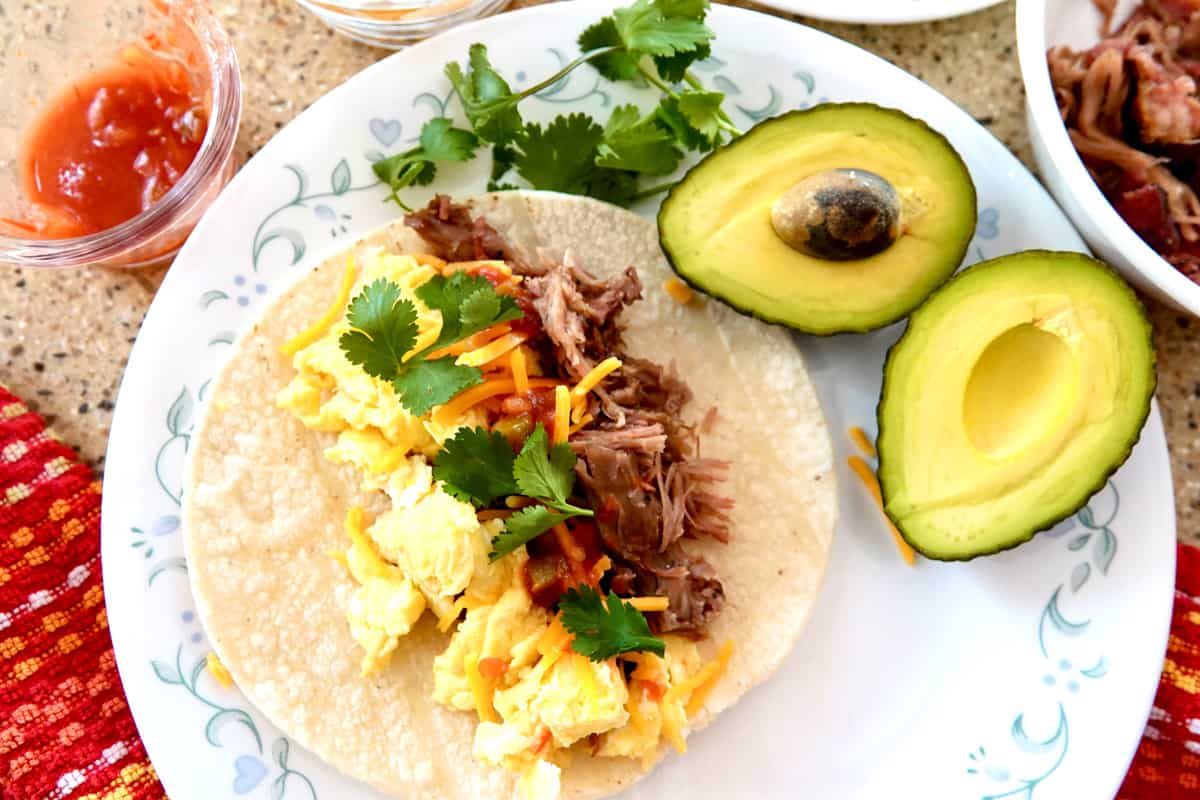 scrambled eggs, pulled pork taco topped with salsa, cheddar cheese and cilantro. Halved avocado