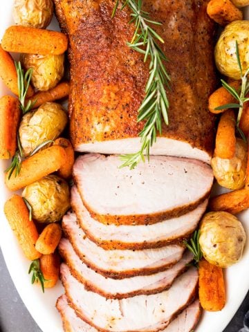 Smoked pork loin on plate with carrots and potatoes with knife and fork