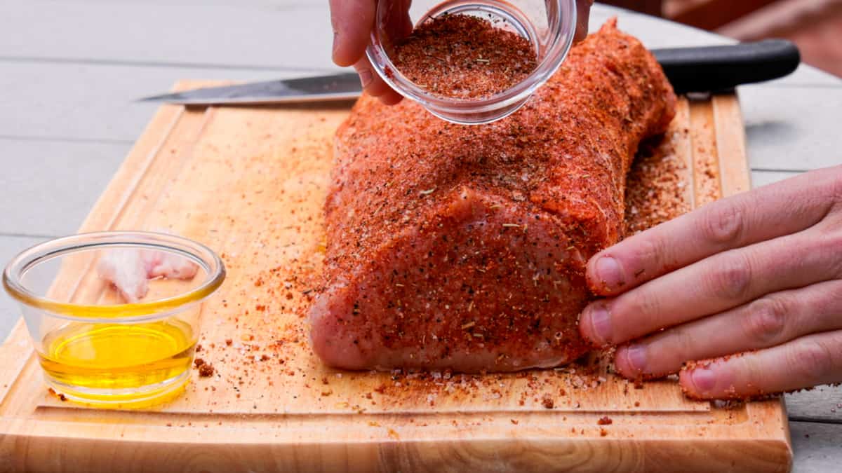Seasoning pork on cutting board before smoking meat