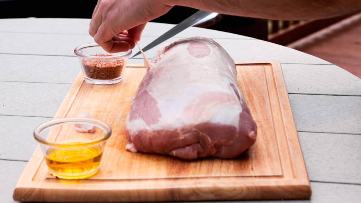 Trimming fat on pork loin atop cutting board