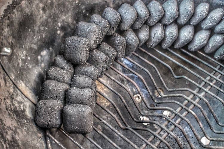 charcoal lined up along the inside of a charcoal grill