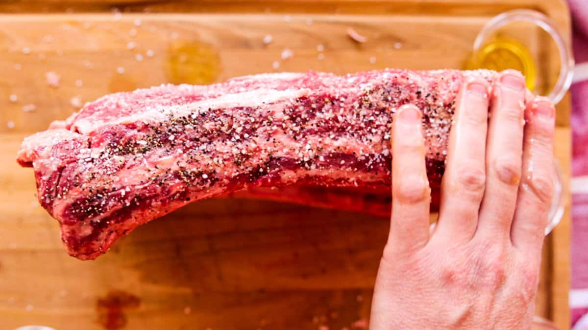 Seasoning the side of beef ribs with salt, pepper, garlic.